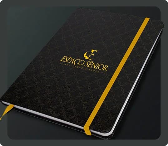 Caderno com a identidade visual do Espaço Sênior em preto e dourado